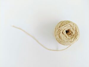 a beige ball of yarn that's unraveled on a white background surface